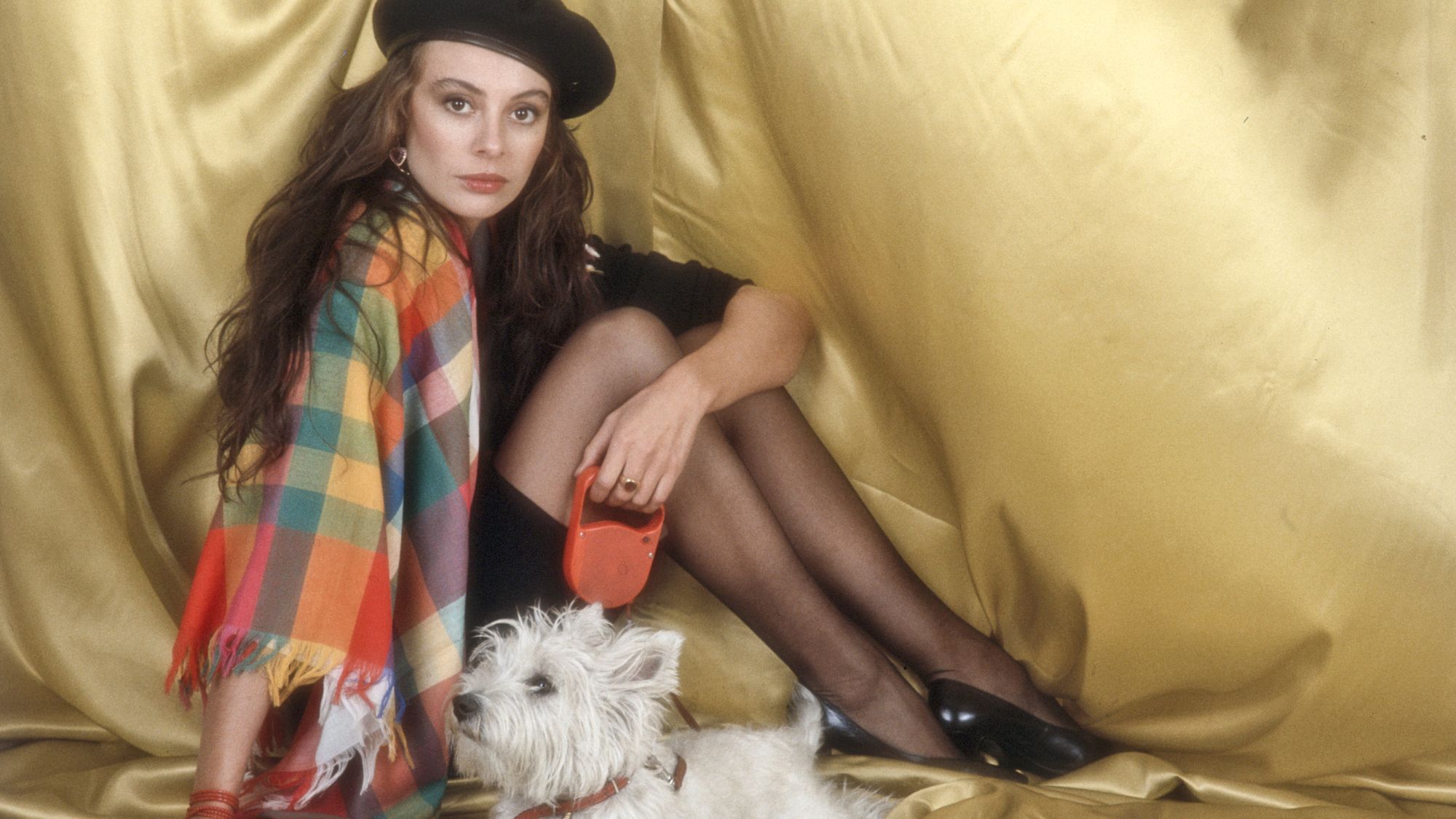 Italian singer-songwriter Alice Bissi sitting on a photo set with a dog on a leash. Italy, 1983.