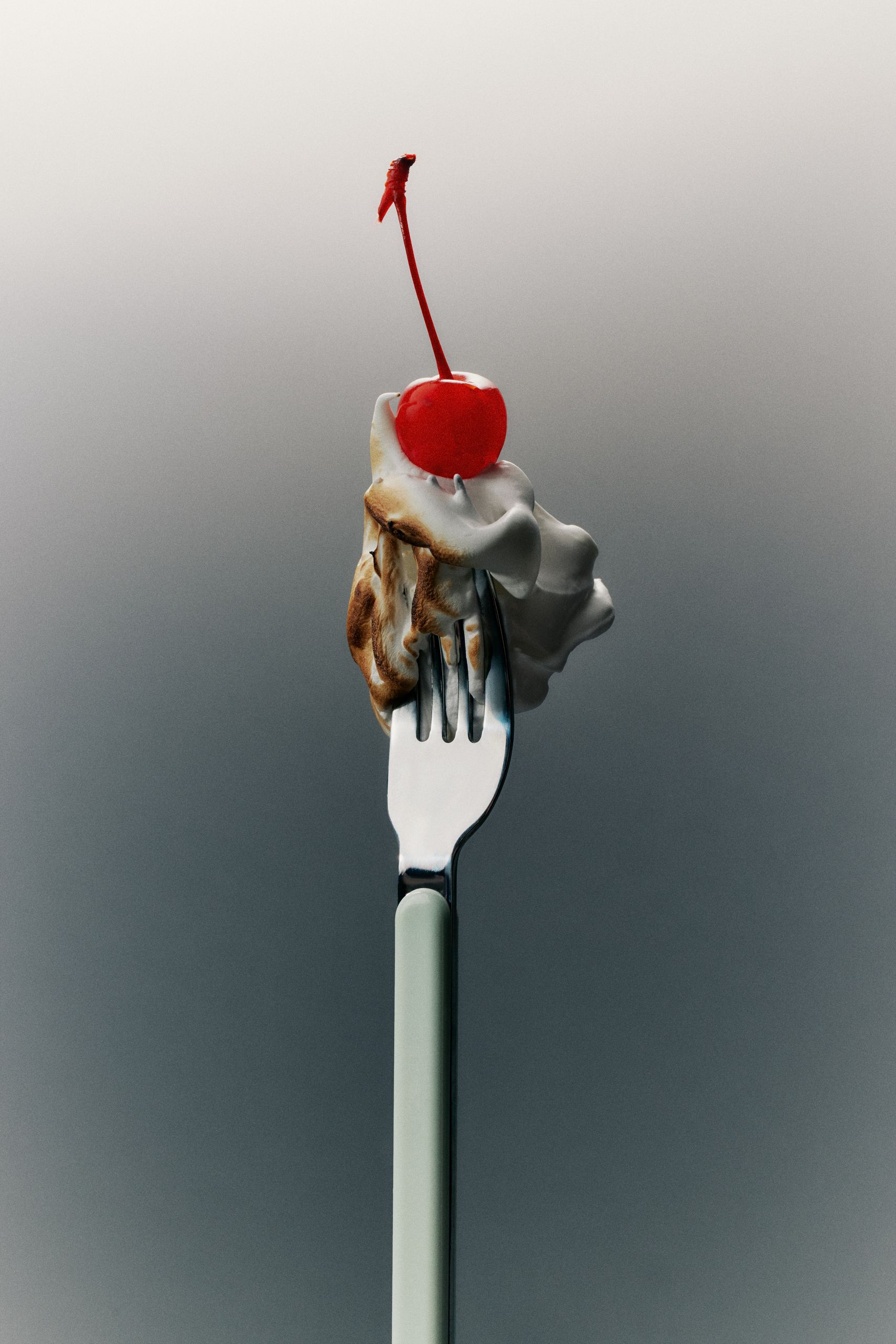 Image of a teal fork with a toasted marshmallow and a cherry on the end of it in front of a faded blue background.