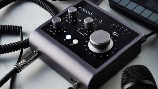 An Audient iD4 audio interface on a white desk with a microphone and MIDI controller