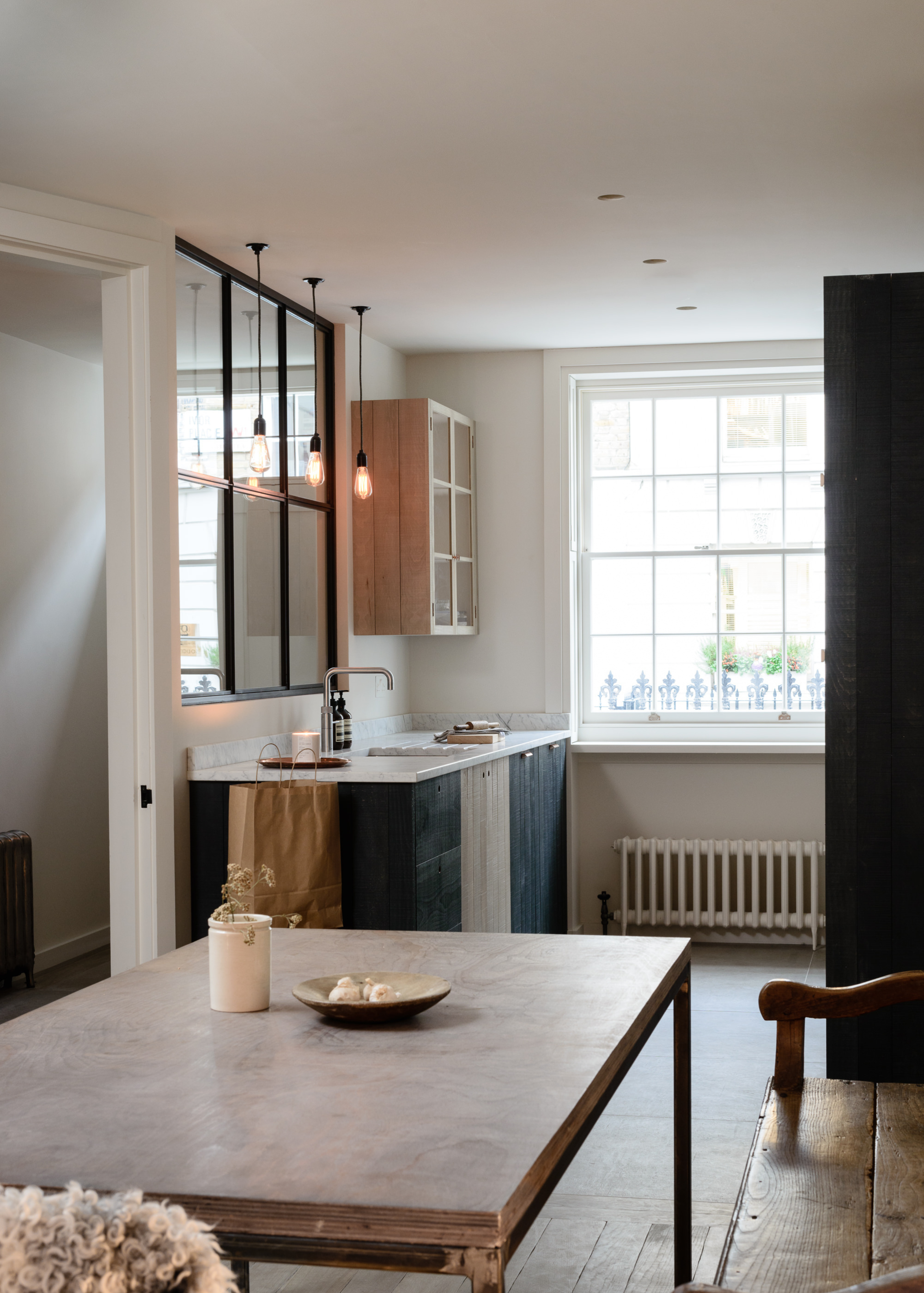A modern wood kitchen in a traditional building with a glazed crittall-style partition between kitchen and hallway