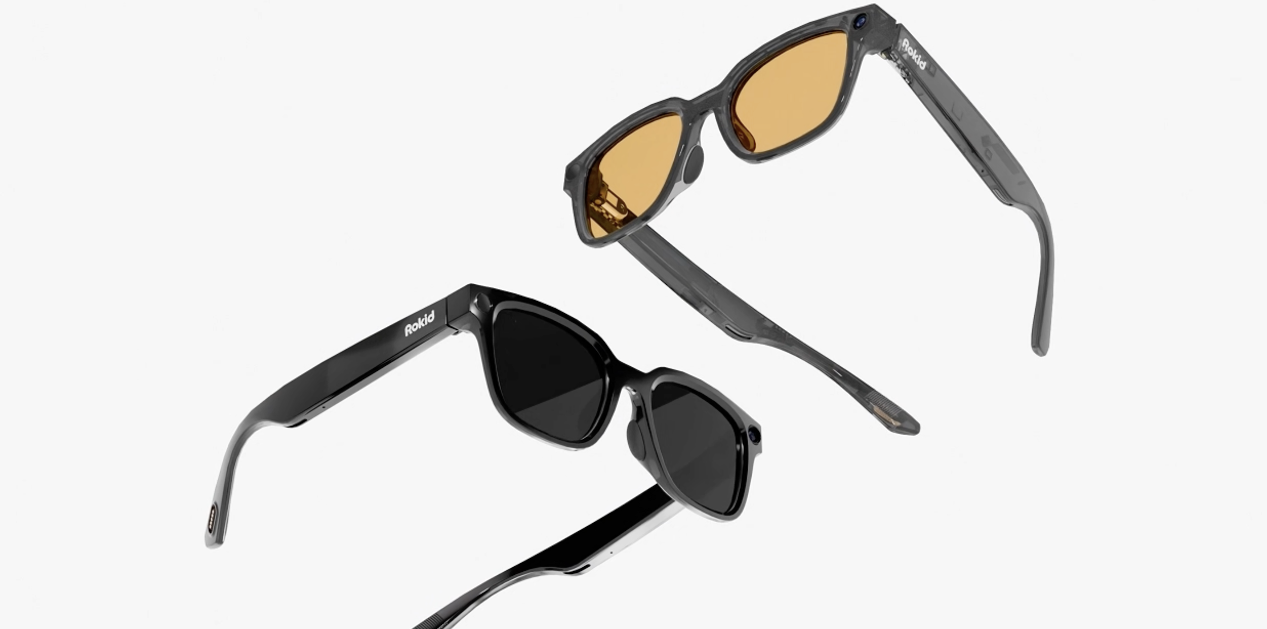 Two pairs of Rokid smart glasses, one with black frames and dark lenses and another with translucent grey frames and orange lenses, are angled to show their side profiles.