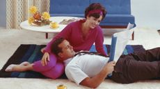 1960s photo of young couple looking at blueprint in living room, smiling