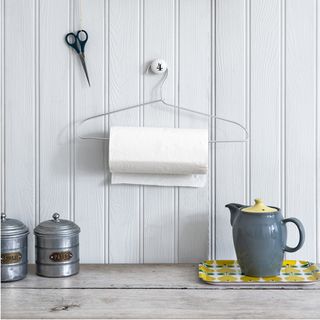 wooden table with teapot and white wall with tissue roll