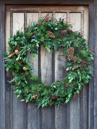 Pinecone and foliage wreath on wooden door