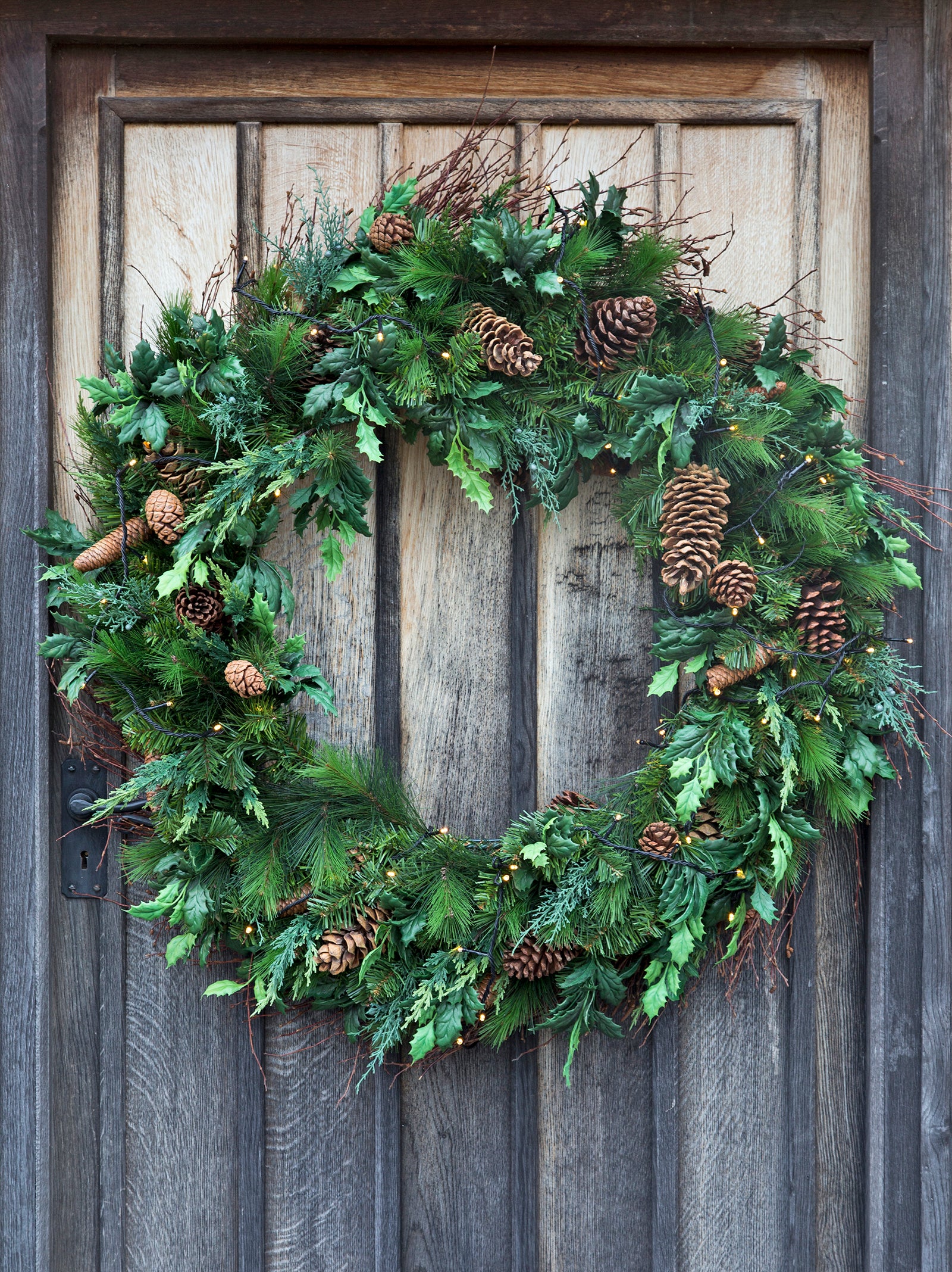 Christmas wreath decorated with pinecones, on old wooden door.