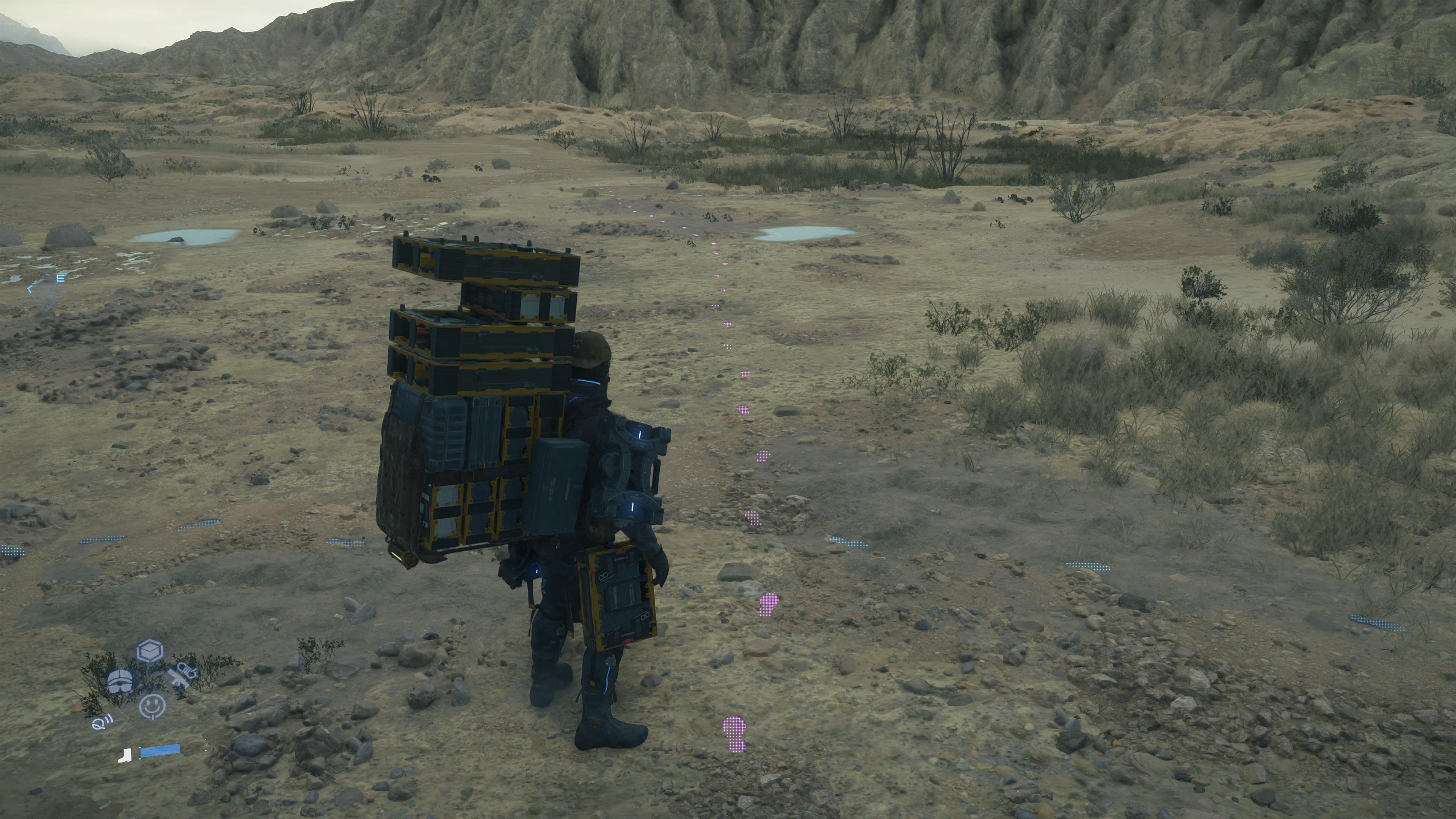 Death Stranding 2 Lou Fragile location: Sam, carrying cargo, looking at purple footprints on the ground.