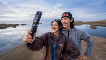 A couple using the Insta360 X6 to capture footage with a lake in the background