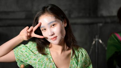 model wearing a sheet mask and making a peace sign
