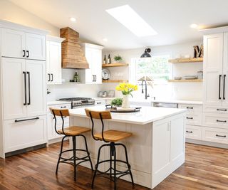 Modern farmhouse kitchen with white cabinets and wood island chairs and range hood