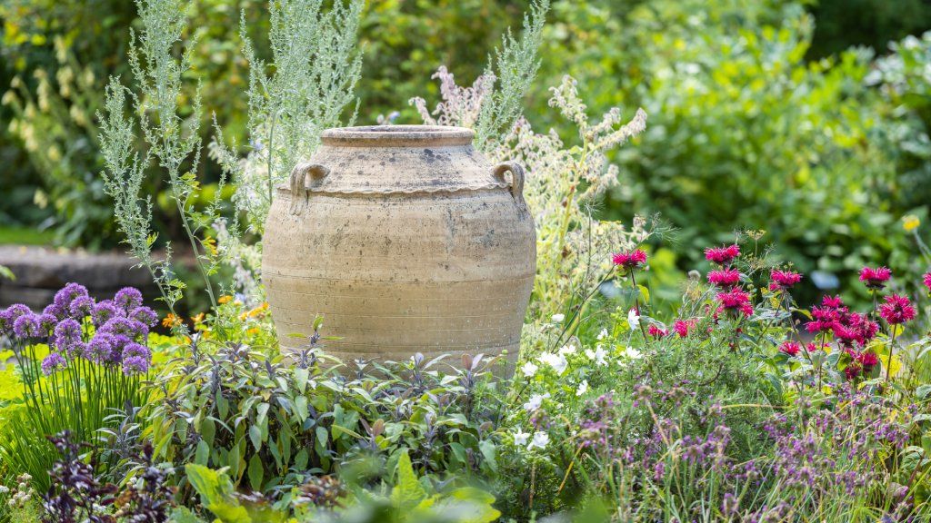 A large decorative urn in an herb and flower garden