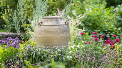 A decorative urn in an herb and flower garden