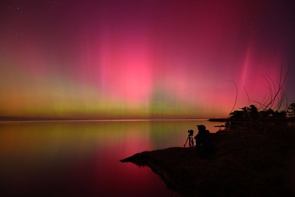 A pink and green sky above a lake.