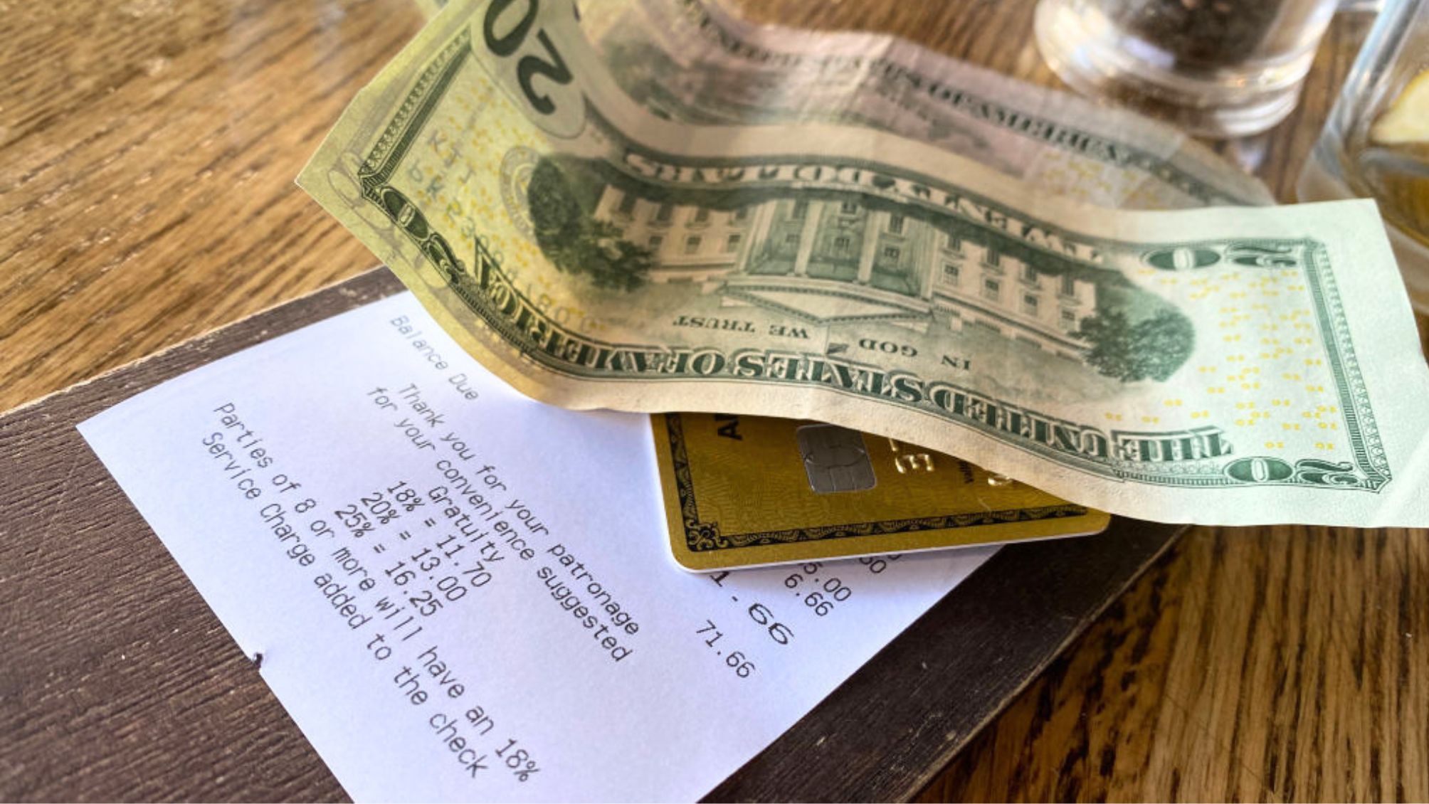 A cash tip and a credit card on top of a dinner bill
