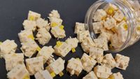 Key switches have spilled out across a black surface from a nearby clear plastic tube. the switches in question are Keychron Silk POM Banana.