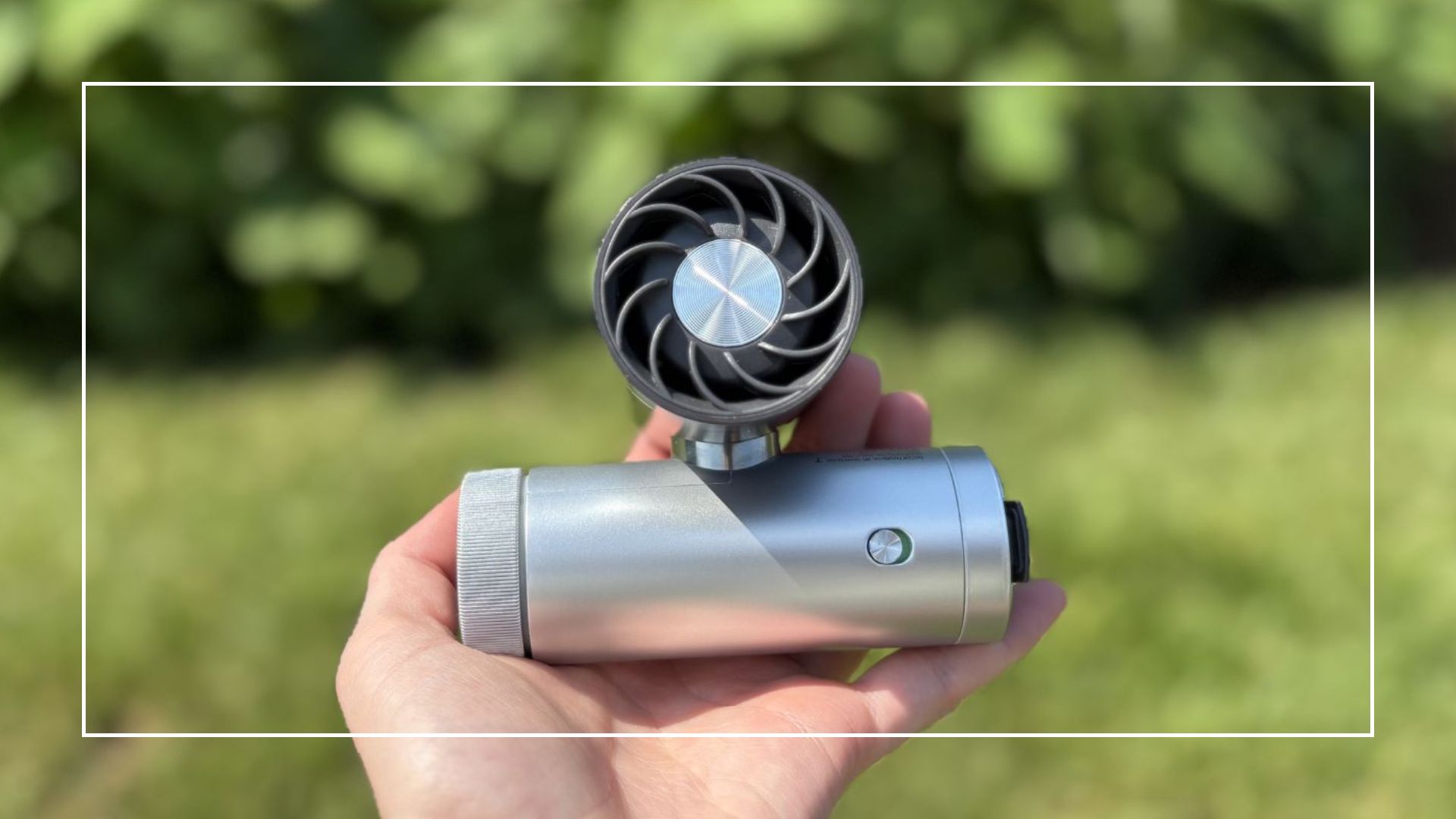 The Shark ChillPill 3-in-1 Fan, Mist &amp; InstaChill System being held in front of a green background