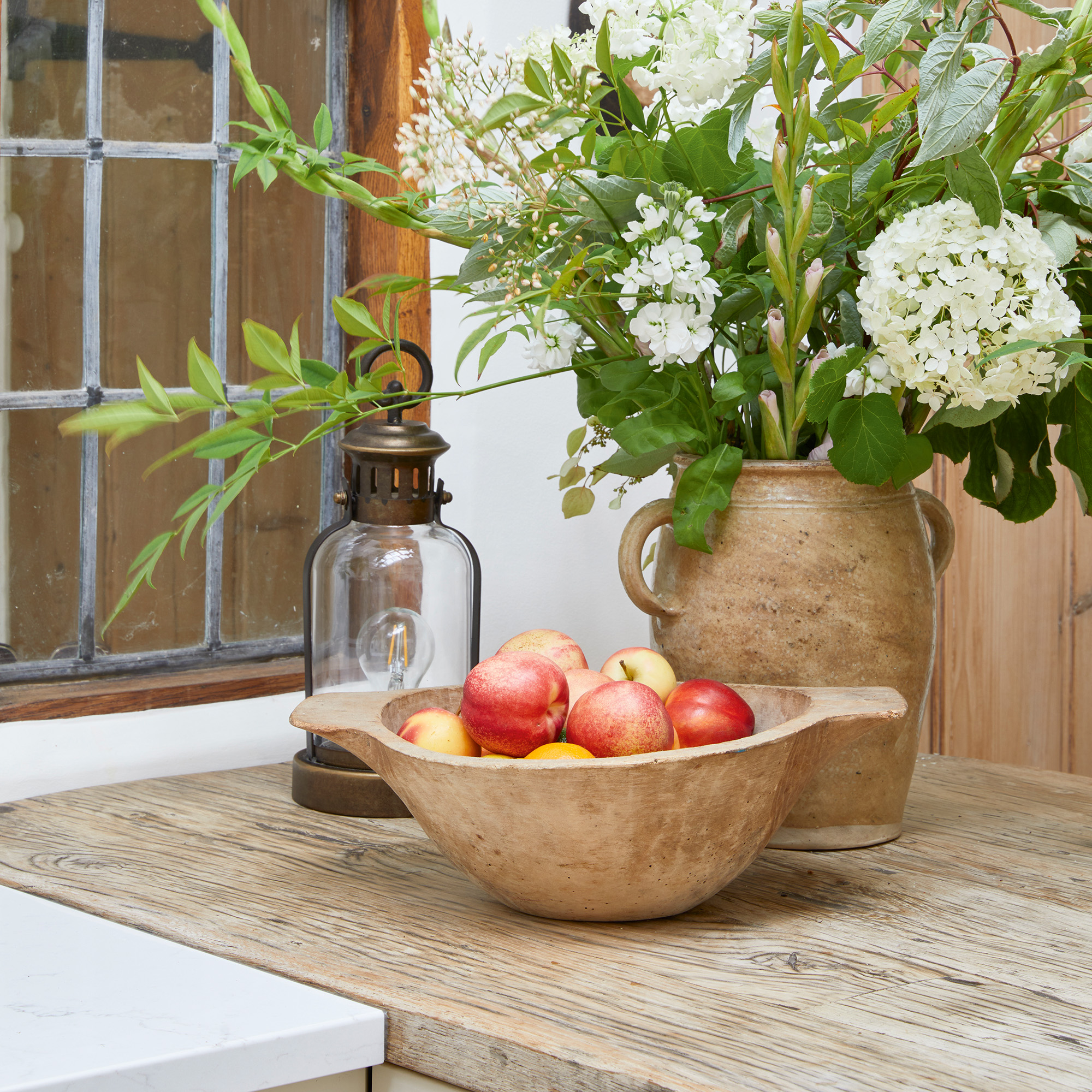 reclaimed wood worktops in kitchen with bowl of apples lamp and vase in with white flowers in kitchen