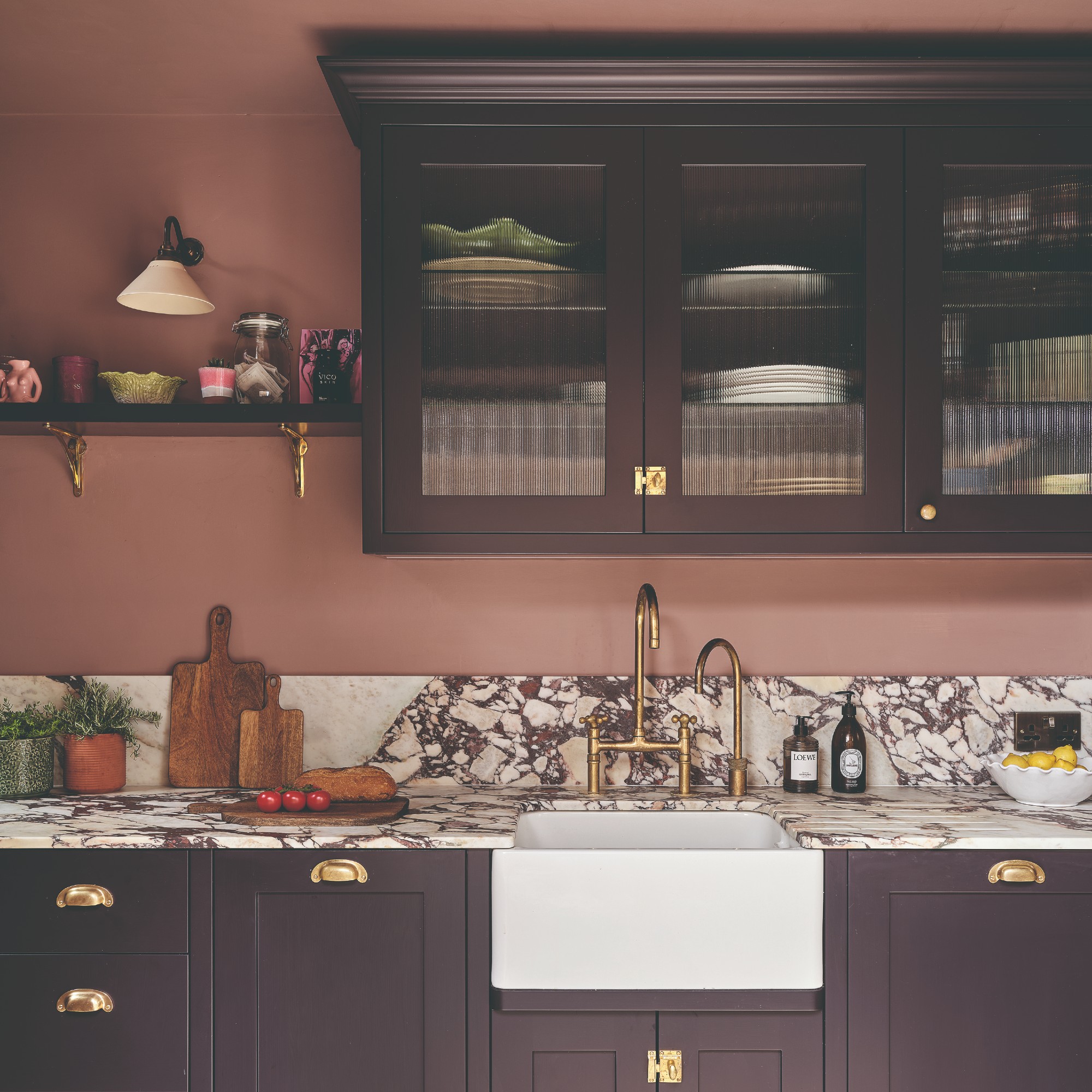 A kitchen with walls painted in Farrow &amp;amp; Ball's Sulking Room Pink and the kitchen cabinets painted in Paean Black
