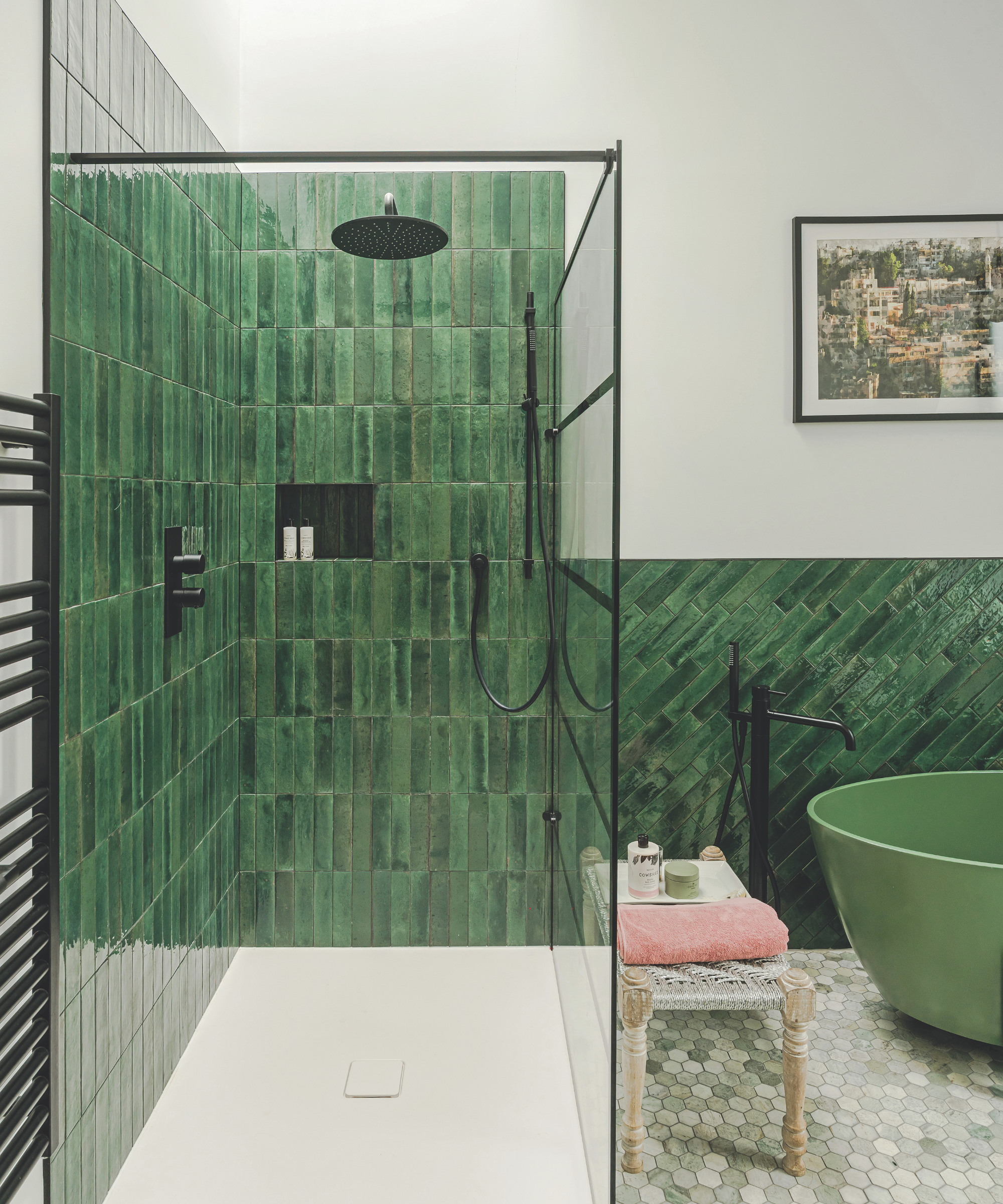 Bathroom with green tiled shower enclosure and green freestanding bath slightly in shot