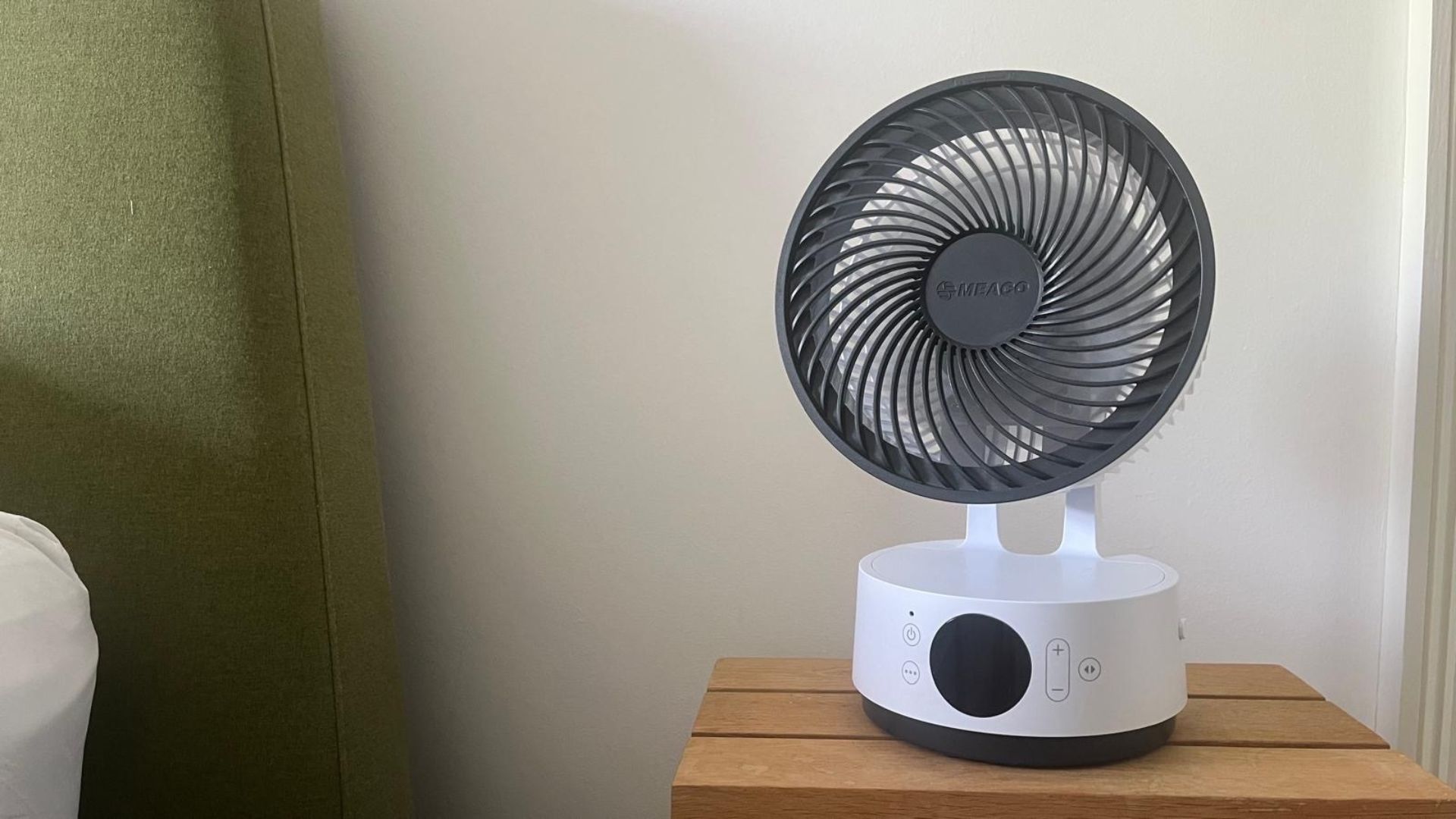 The Meaco Sefte 6 Inch Portable Fan next to a green bed