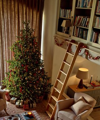 living room with high ceilings and tall bookcases decorated for christmas with a large tree and paper chain garlands