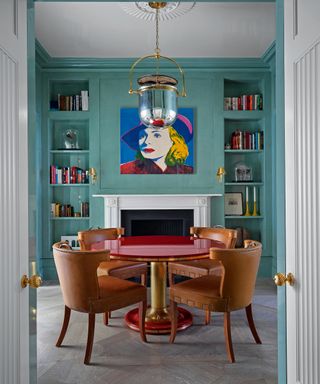 turquoise dining room with white fireplace, circular red table and brown leather dining chairs