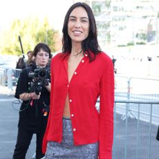 Alexa Chung arrives at the Prada runway show in Milan wearing a red button-down with a sparkly knee-length skirt and black slingback heels.
