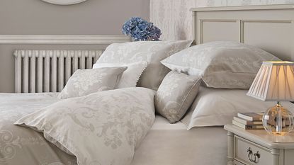 dove grey bed frame with grey printed bed linen, round mirror and bedside table with lamp - Laura Ashley