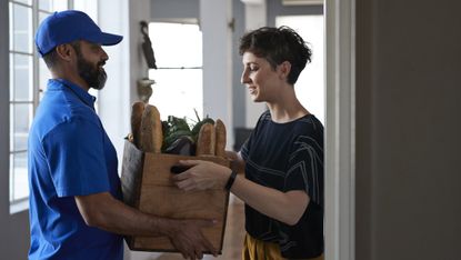 Woman receiving groceries from delivery person - stock photo
