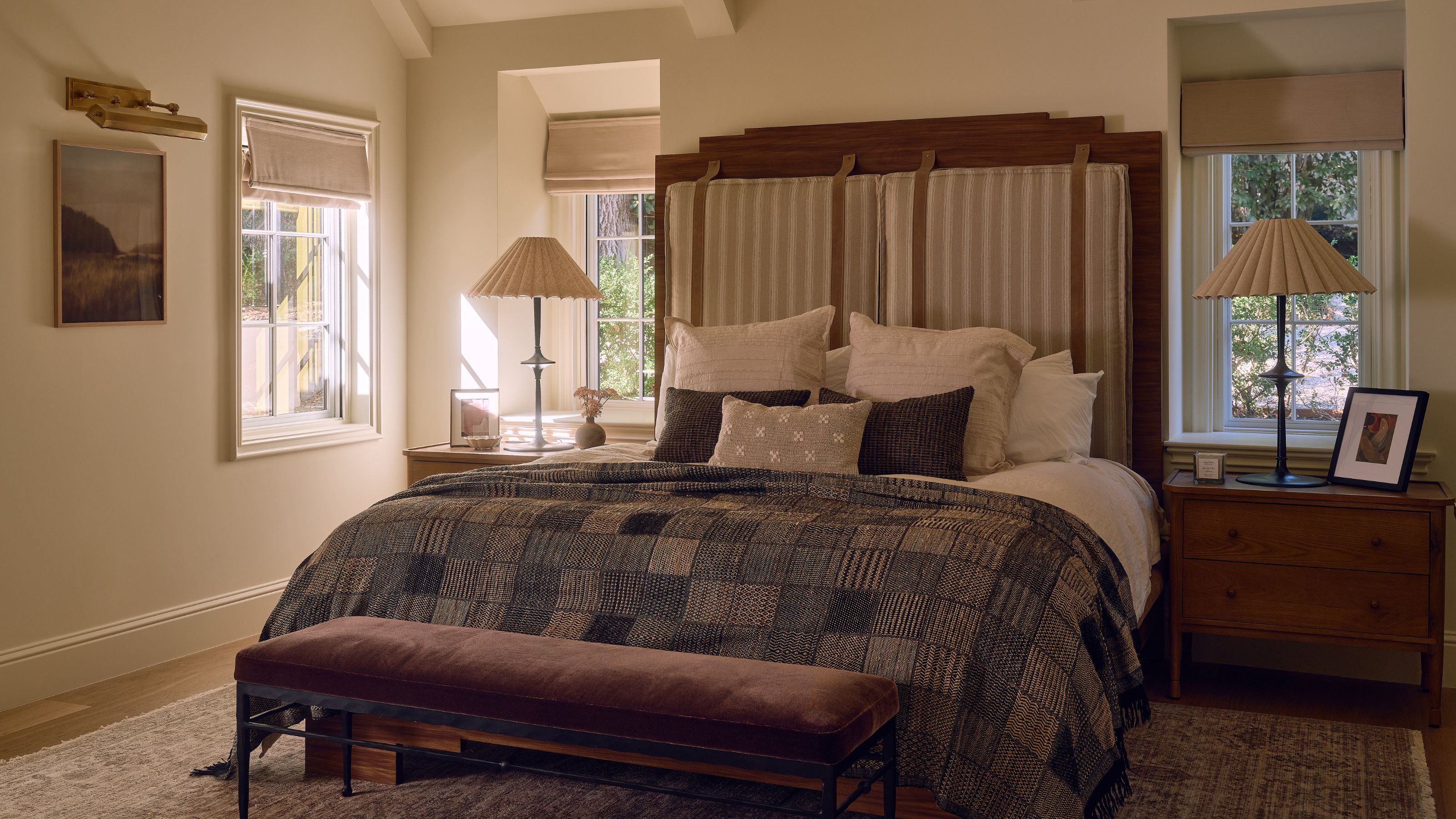 a large primary bedroom suite with a tall wooden and upholstered bed with patchwork quilt