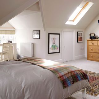 attic bedroom with white walls and wooden vanity