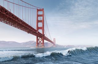 A surfer rides a wave beneath the Golden Gate Bridge in San Francisco, California.