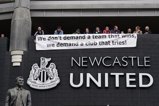 Supporters hold a banner up which reads "We don't demand a team that wins, we demand a club that tries".