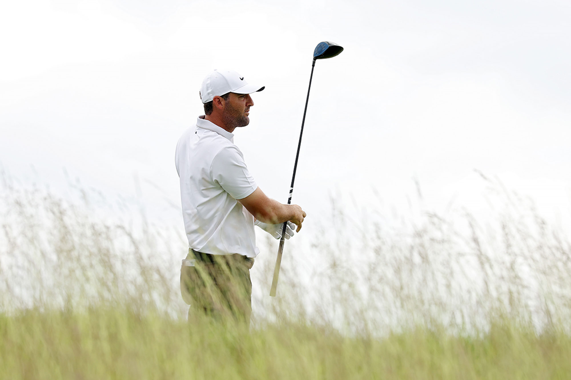 Scottie Scheffler holding his driver and watching as his golf ball travels away from the tee box during a practice round at the 2025 US Open at Oakmont Country Club