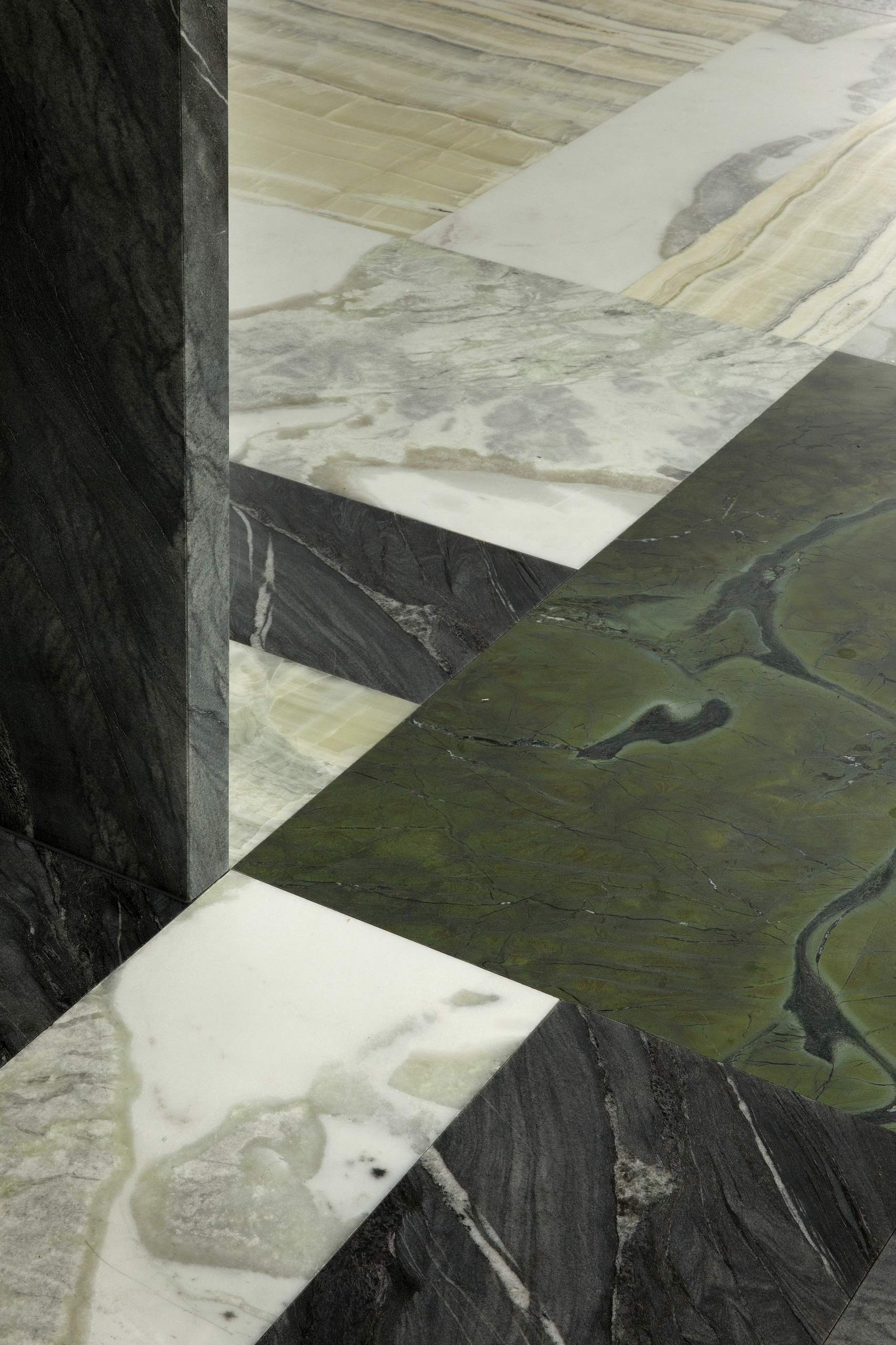 Close-up of a stone floor with a mix of green, black, and white tiles.