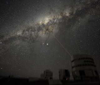 Three of the four 8.2-m telescopes forming ESO's VLT are seen dimly, with a laser beaming out from Yepun, Unit Telescope number 4. The laser points at the Galactic Center of the Milky Way, our galaxy. The bright object at center is Jupiter, while the othe