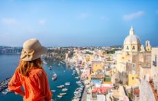 Woman with hat looking at stunning panoramic view of Procida Island, Naples, Italy.