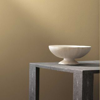 A dark beige room with a stone table and ceramic bowl