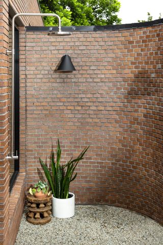 outdoor shower with curved brick wall and gravel flooring