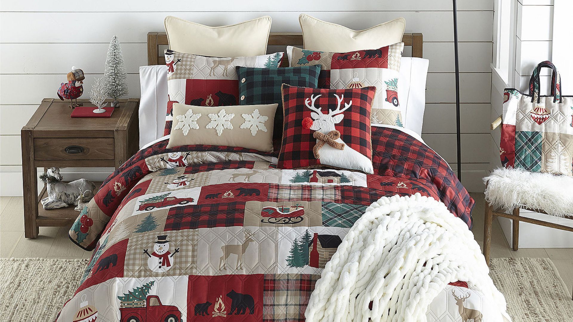 A red, green, and tan Christmas bedding quilt set with patches filled with Christmas design elements with a red and black plaid reverse side.