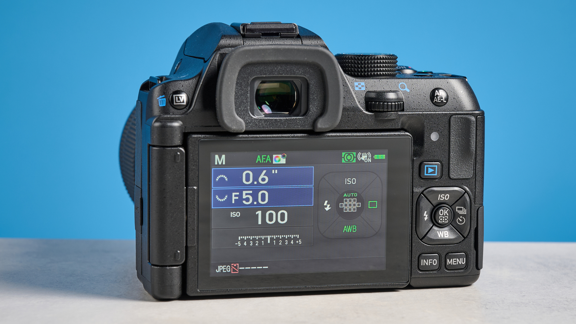 Pentax KF DSLR camera photographed on a blue background