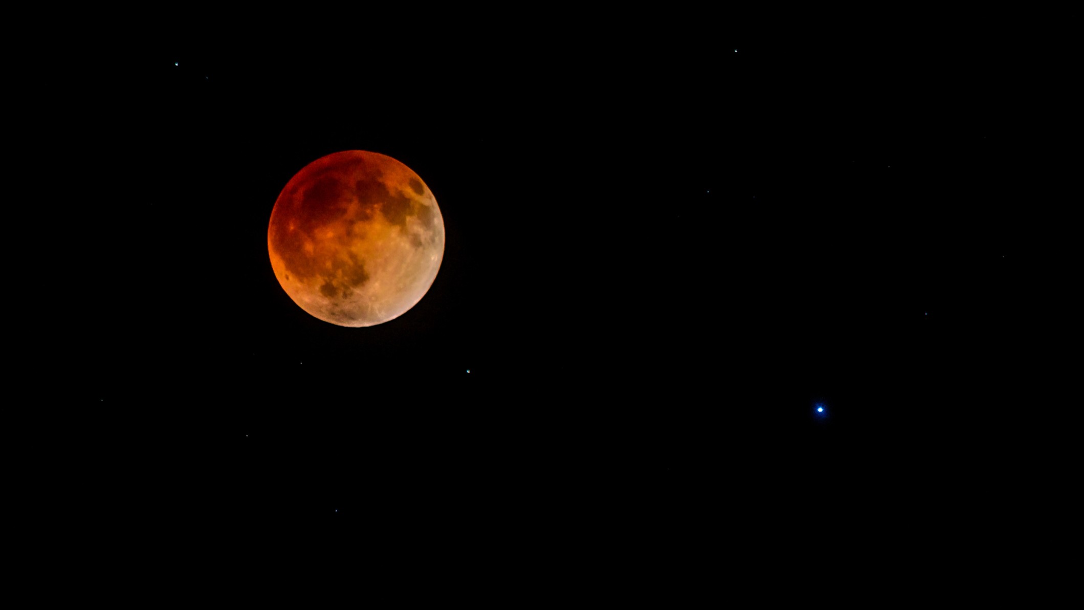 red hued moon on the left and a bright blue star, spica on the right.