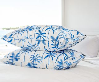 Palm tree pattern on a silk pillowcase against white bedding.