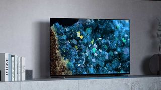 the Sony A80L TV on a surface in a living room, near some generic ornaments