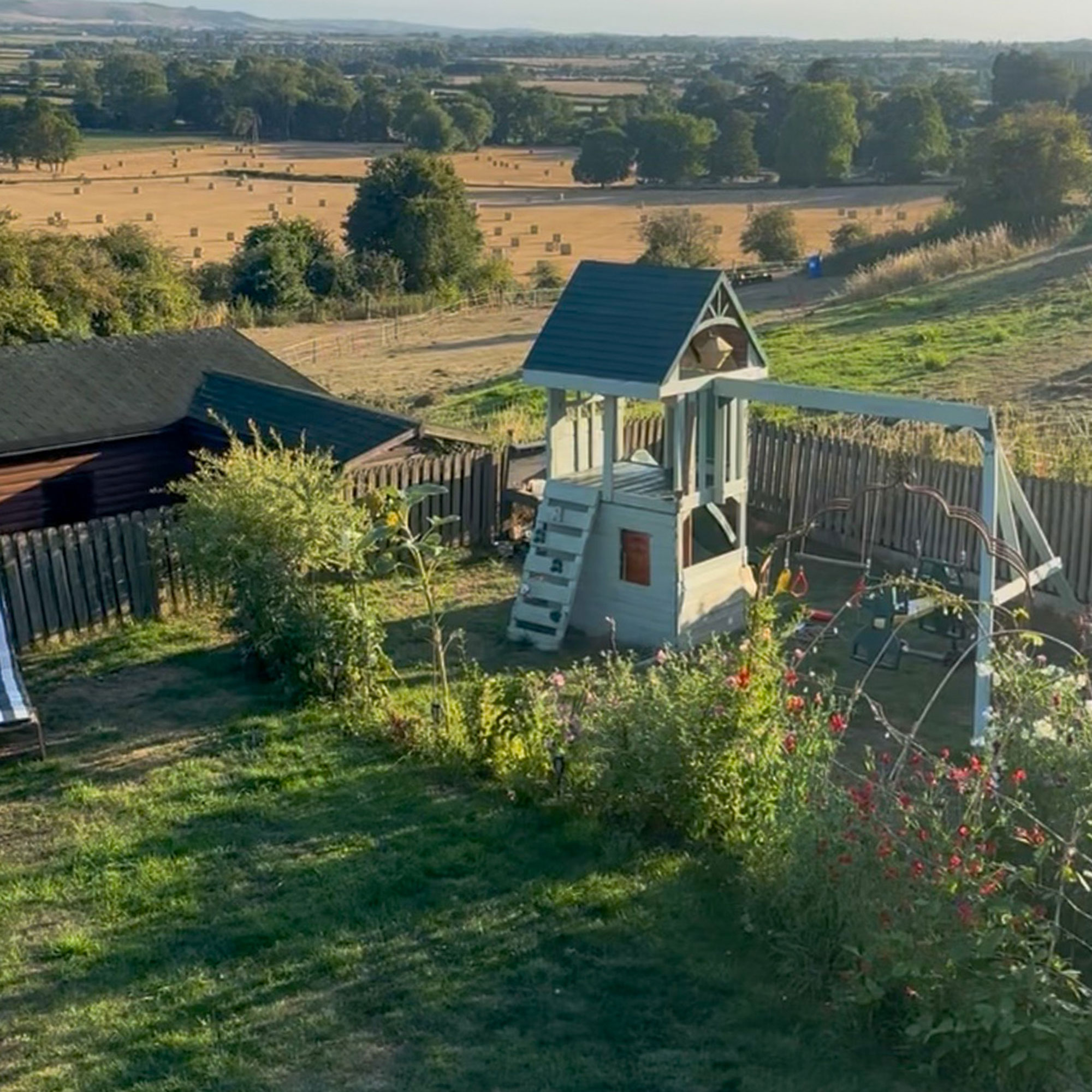 View of child playhouse in garden with backdrop of rolling hilly fields