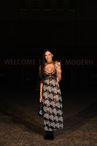 Demi Moore wearing a lace patterned maxi dress with her dog at the Gucci Cruise 2025 show.