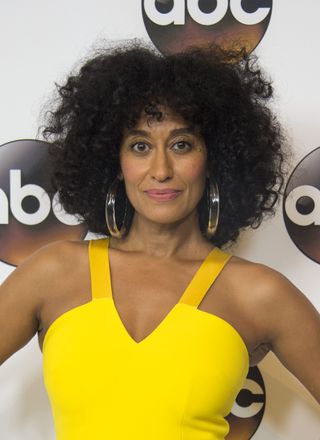 Tracee Ellis Ross with a curly bob hairstyle in a bright yellow dress.