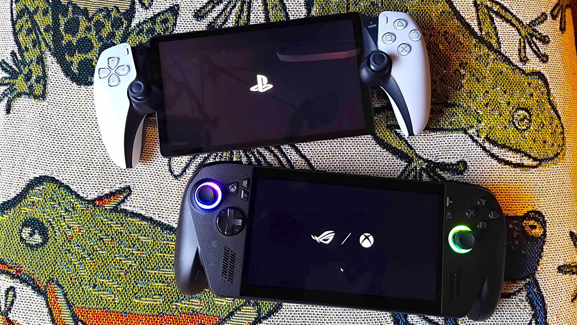 Picture of the PlayStation Portal at top and ROG Xbox Ally X at the bottom, sitting on a throw with a frog pattern.