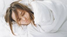 Woman wrapped up in white sheets, sleep & wellness tips