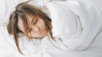 Woman wrapped up in white sheets, sleep & wellness tips