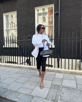 Woman wearing a white button down with black capri pants and mules.